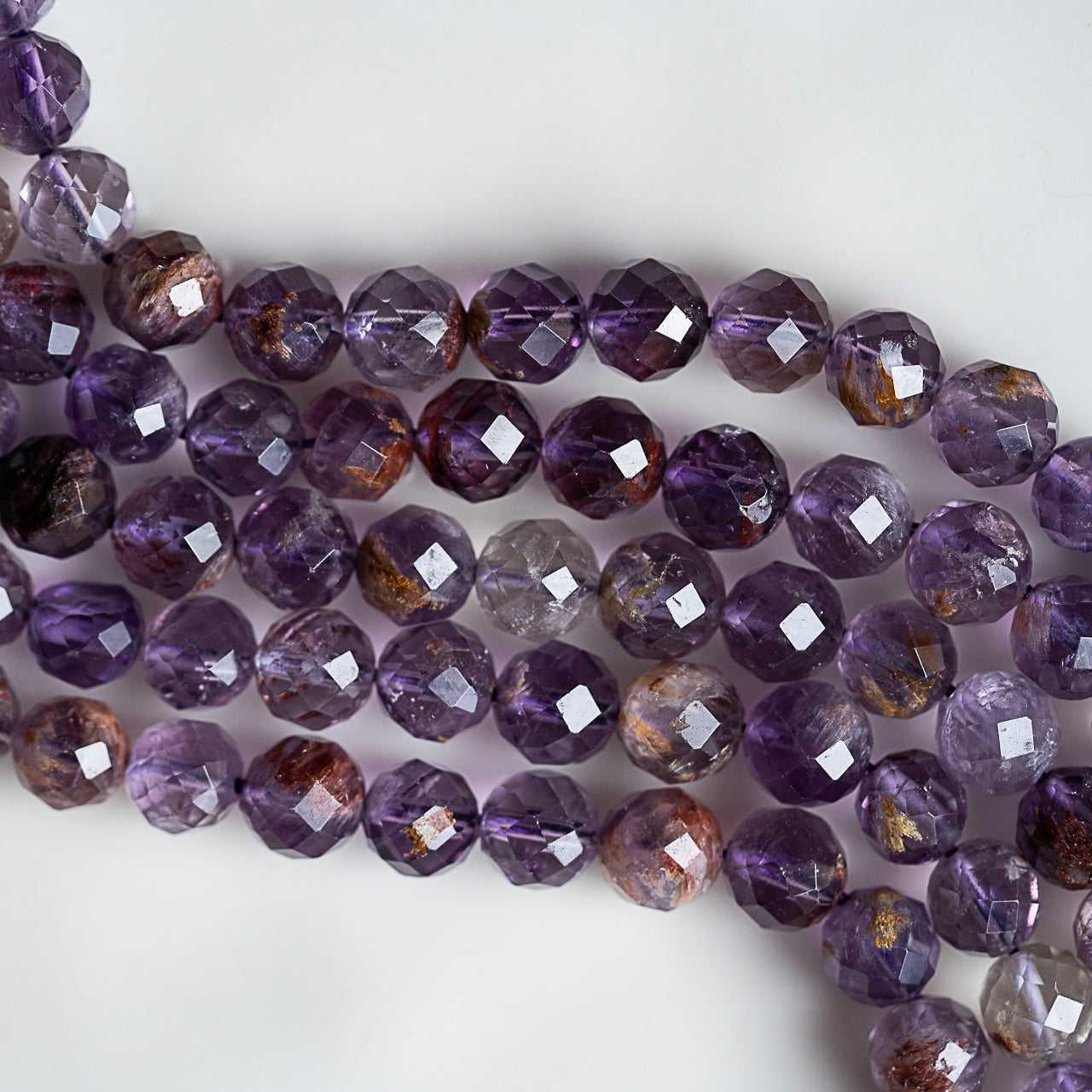 Perles rondes facettes en Améthyste à inclusions de 7,5 mm ( 1/2 rang de env 24/25 perles )