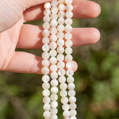 Perles rondes lisses de nacre blanche de 6 mm ( rang de env 62 perles )